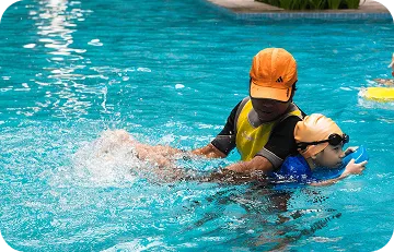Swimming instructor supporting a young child in the pool