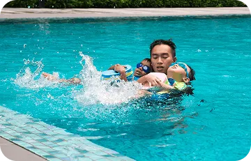 Instructor holding and guiding two children learning to float